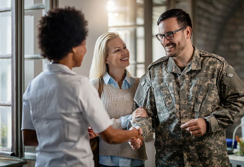 Happy veteran and his wife greeting doctor.